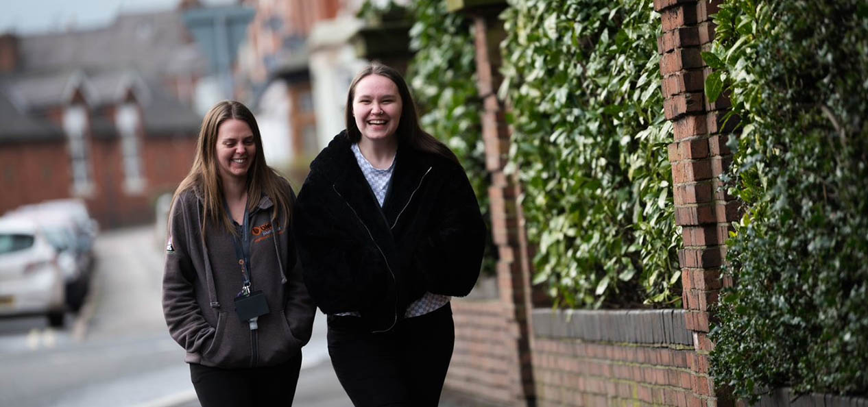 Two young women laugh as they walk down a street