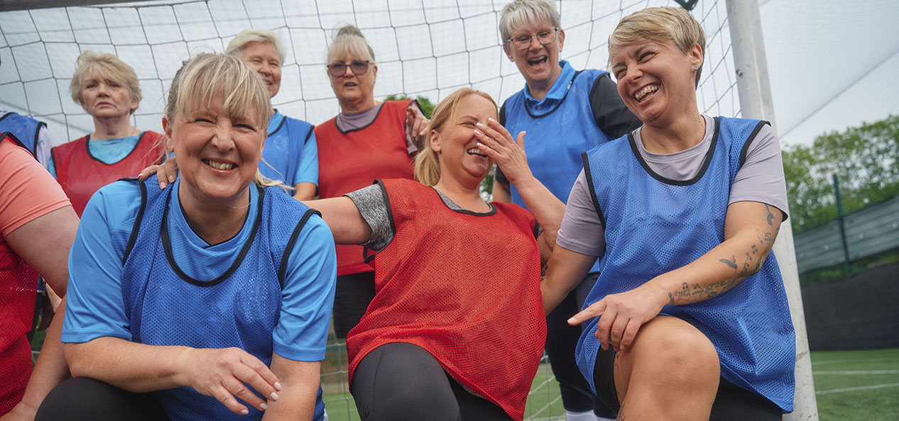 A woman's football team laugh as they pose for a team photo
