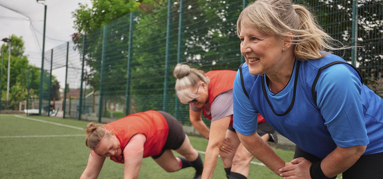 Three women stretch before a game of walking football