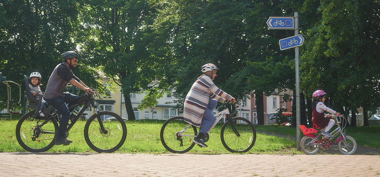 A family, husband, wife and two daughters, ride their bikes along a bike path.