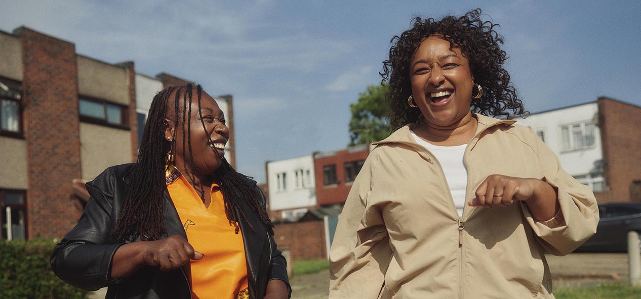 A woman and her daughter smile as they walk outside