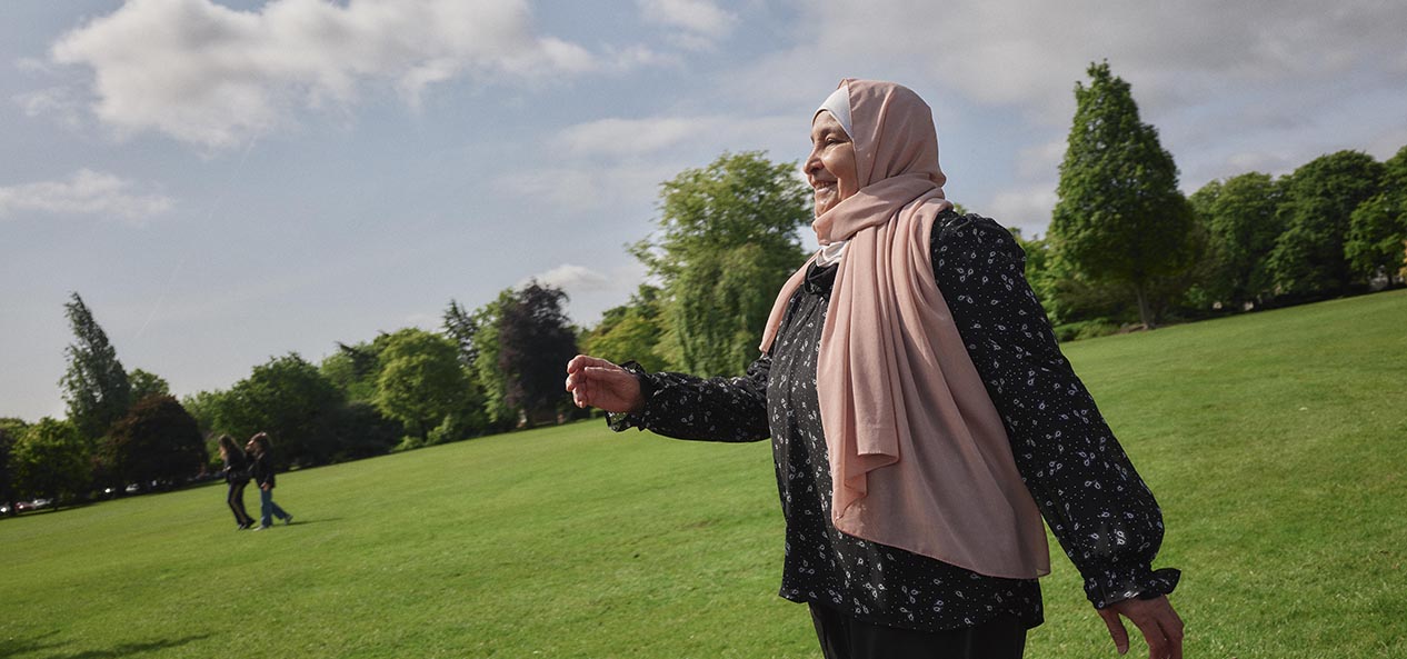 A woman wearing a head scarf walks in a park