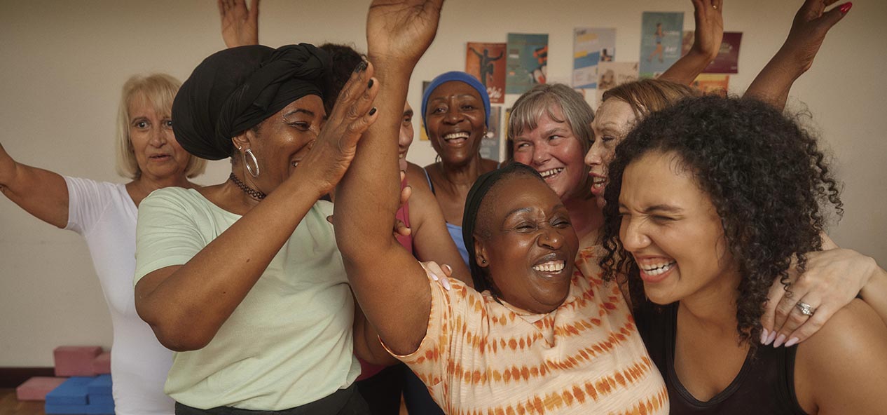 A woman smiles as she dances with a group of other women in a studio
