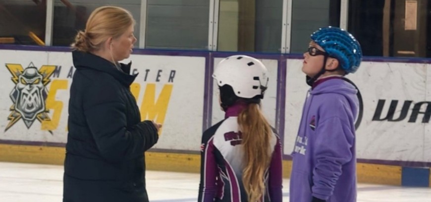 Altrincham Speed Skating Club coach Sally Sherard-Bornshin talks to two young skaters on the ice.