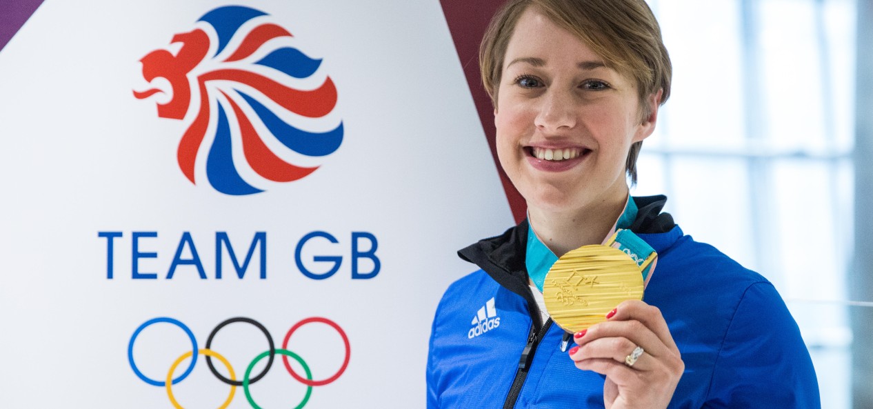 Lizzy Yarnold poses with her gold medal in front of a Team GB sign at the 2018 PyeongChang Winter Olympic Games.