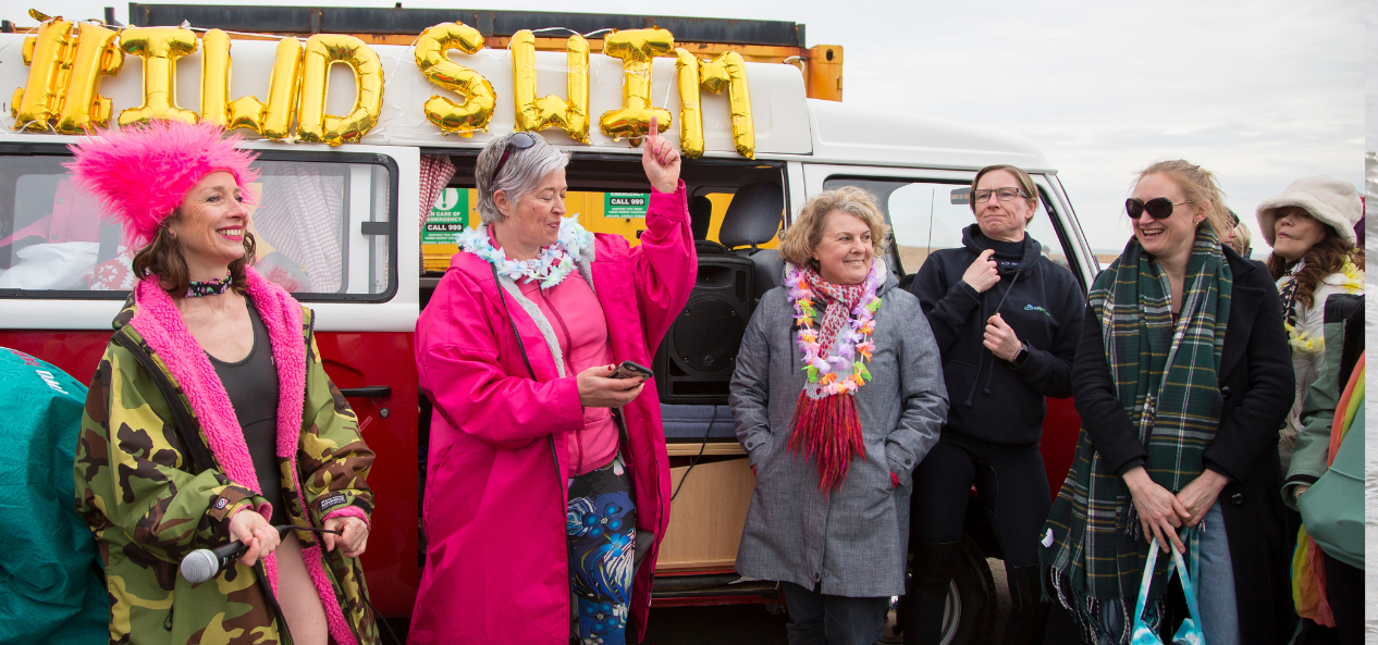 Group of women take picture in front of van