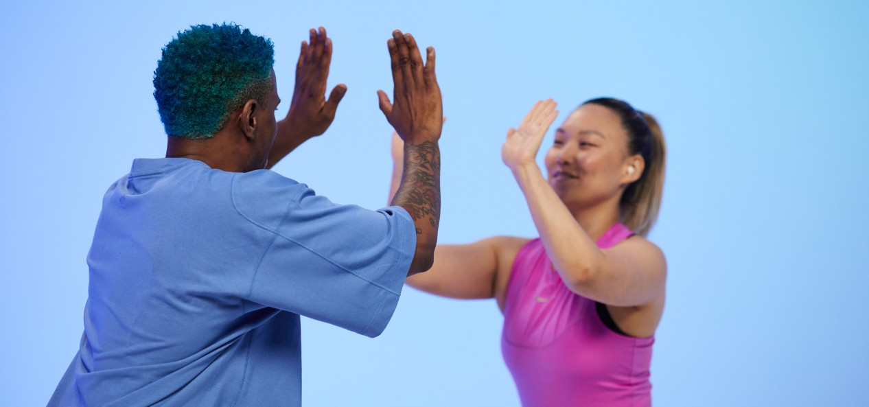 Two Nike trainers high-five during a Studio You video PE lesson.