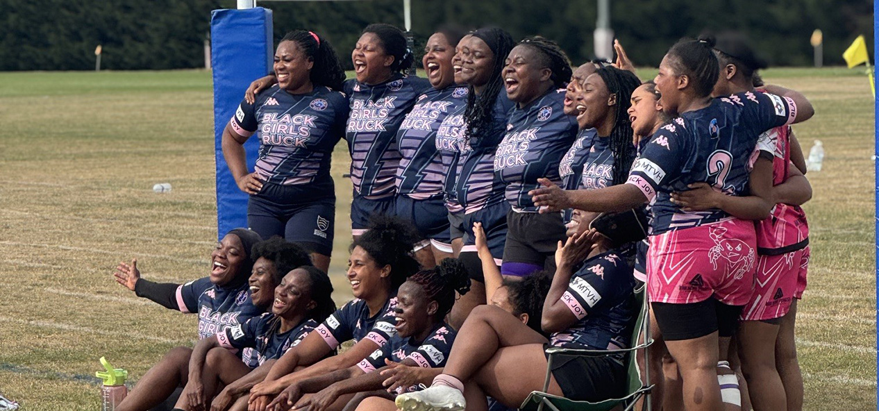 Players from the Black Girls Ruck rugby team pose together on an outdoors pitch