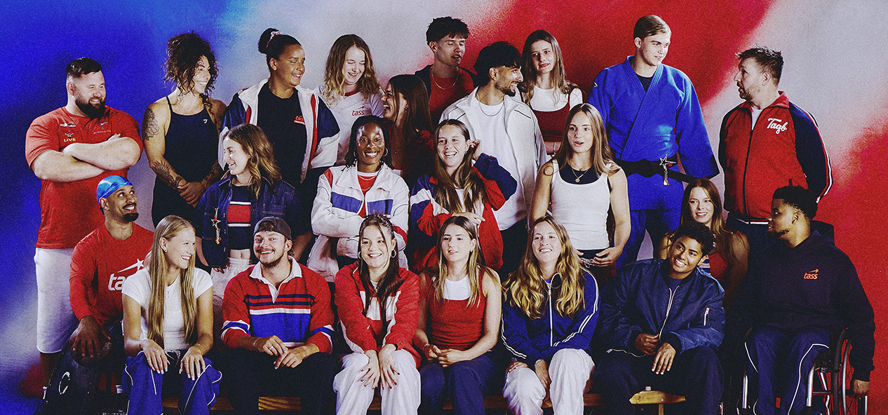 Group image of the Class of Tass athletes. All wearing a variation of red, white and blue, stood against a red, white and blue backdrop.