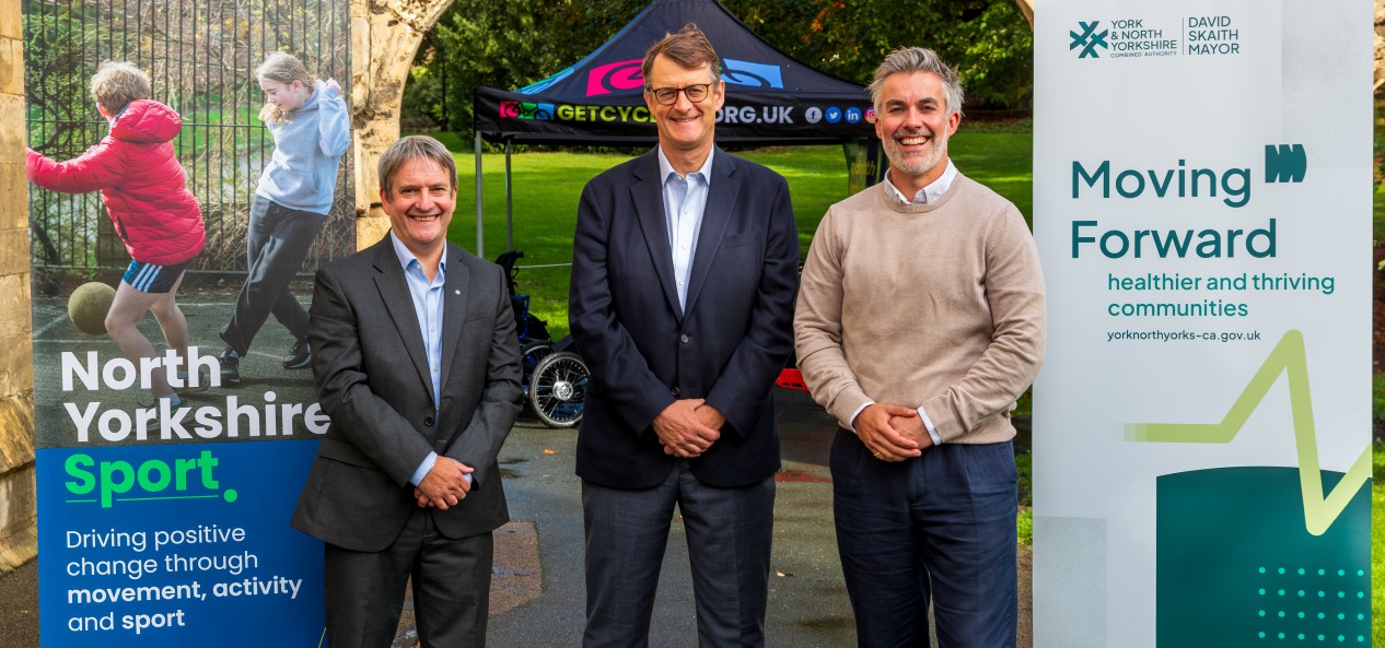 The chief executive of North Yorkshire Sport, David Watson, poses for a photo with Sport England chief executive Simon Hayes and the Mayor of York and North Yorkshire, David Skaith, with pull-up banners promoting the two North Yorkshire organisations on either side of the group.