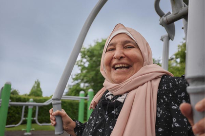 A woman wearing a headscarf uses a chest press machine in a park gym
