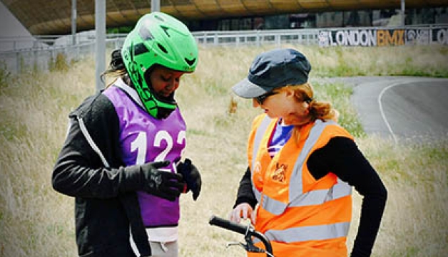 A volunteer speaks to a teenage BMX rider