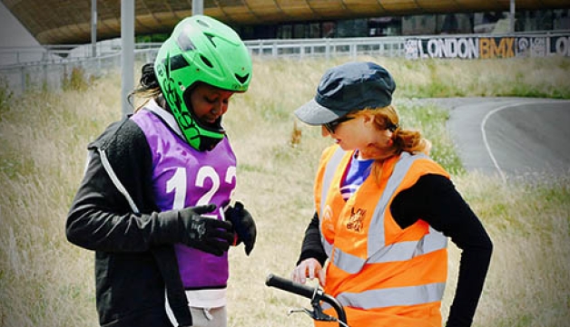 A volunteer speaks to a teenage BMX rider