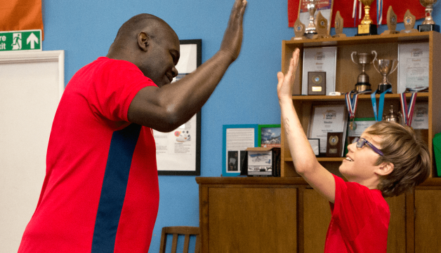 Child and coach high five during table tennis game