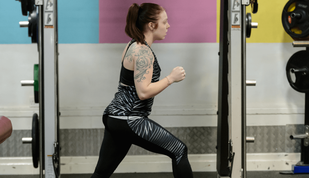 Girl working out in gym in front of weights rack