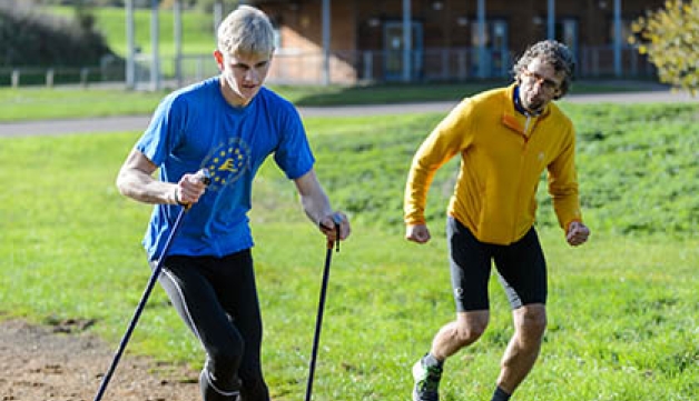A Nordic walker with a coach running alongside
