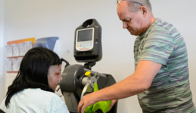 Man helping woman use exercise equipment