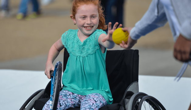 Young girl in wheelchair receiving ball
