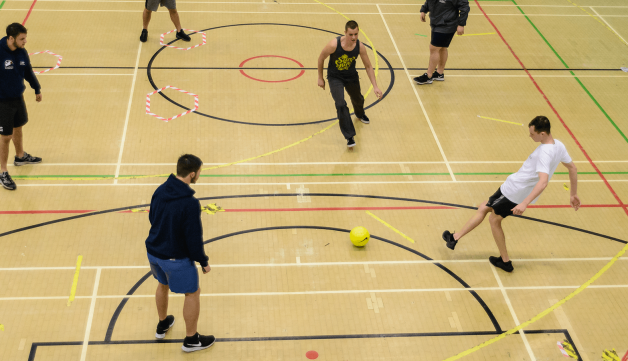 Young men playing football in sports hall