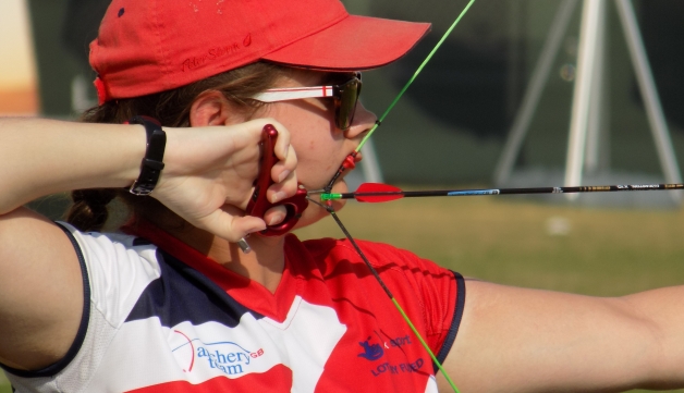 young woman shooting bow and arrow in England kit