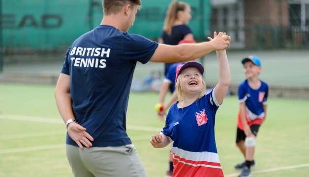 coach handing a child a tennis ball