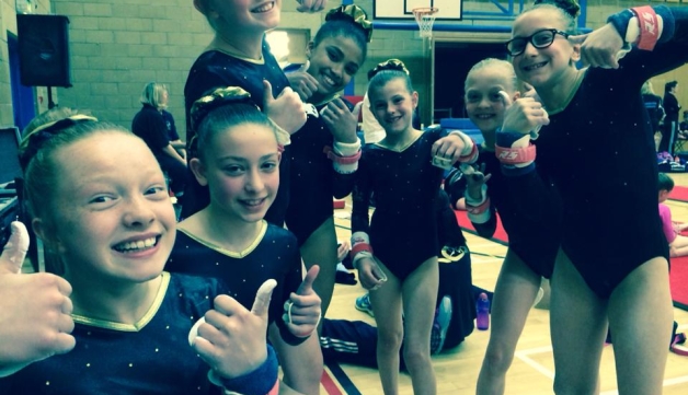 girls in gymnastics kit giving thumbs-up