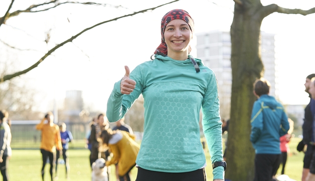 A woman gives a thumbs up to the camera after completing a parkrun