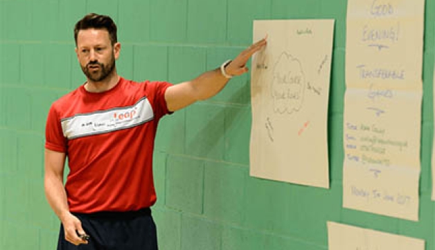 A man who works in sport pointing to a poster