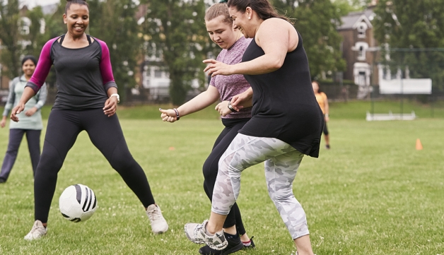 A group of women have a kickabout in a park