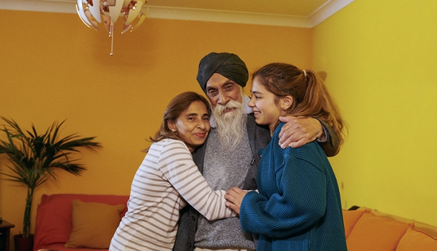 A family of three embracing in their living room.