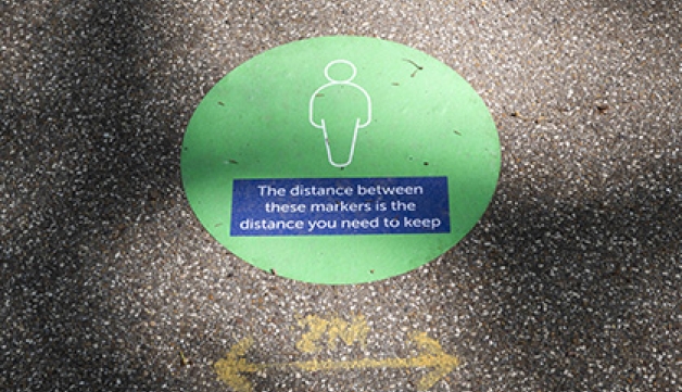 A painted sign on the ground instructing people to keep two metres apart.