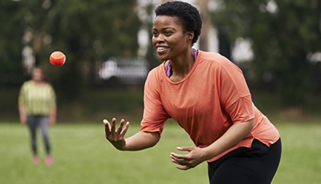 A woman throwing a ball while playing softball in a playing field.