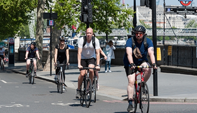 Cyclists ride in a line through a city.