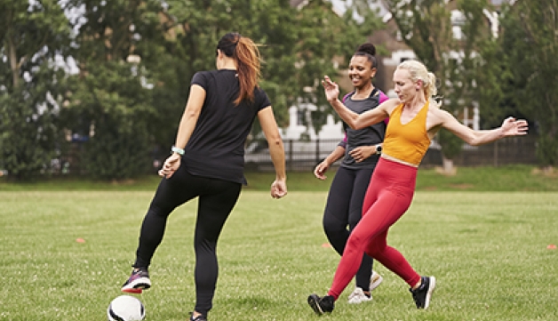 A group of women playing football in a park.