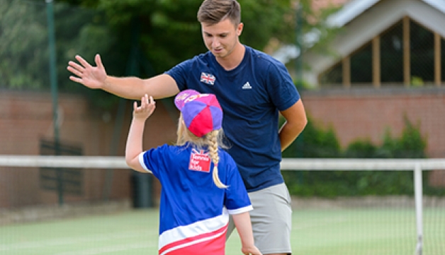 A tennis coach high-fives a girl during a coaching session.
