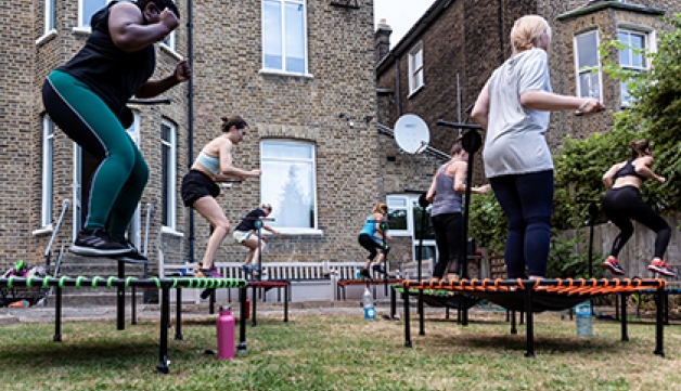 A group of women participate in a mini-tramp exercise class outdoors