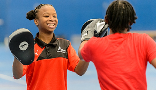 Two schoolgirls boxing inside a sports hall.