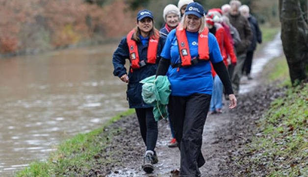 A group of adults walk along a towpath