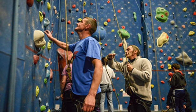 Leaders hold ropes at the foot of a climbing wall
