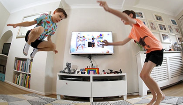 Two boys perform exercise in their living room as part of Joe Wicks' 'PE with Joe' programme.