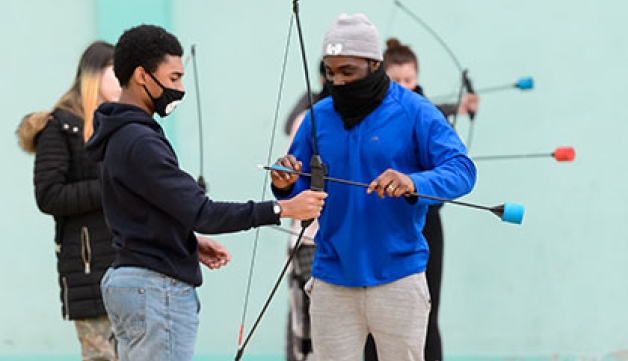 Two boys set up for archery using large cushions instead of arrow heads