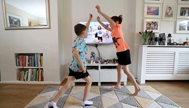 Two boys perform exercise in their living room as part of Joe Wicks' 'PE with Joe' programme.