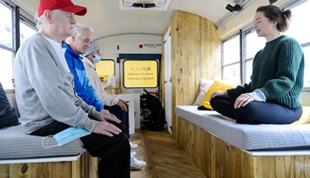 A teacher and students practise yoga in a bus
