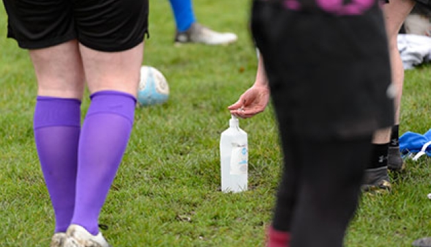 A rugby player uses hand sanitiser at the side of the pitch