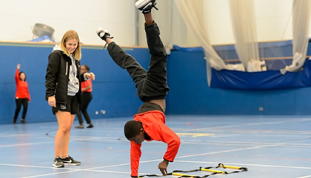 A boy performs a cartwheel in a school PE lesson