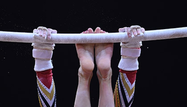 A gymnast works the bar