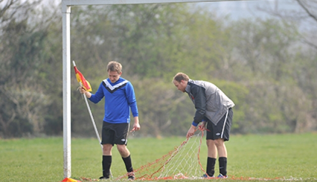 Players set up the nets and corner flags for a football match