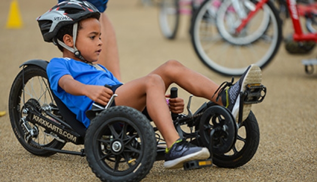 A boy rides an adapted recumbent tricycle