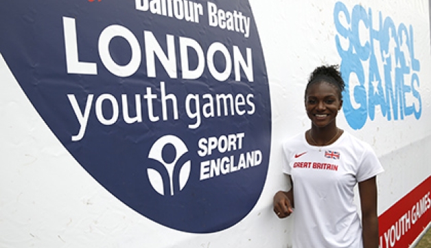 Dina Asher-Smith at the 2015 London Youth Games, standing in front of a sponsor banner