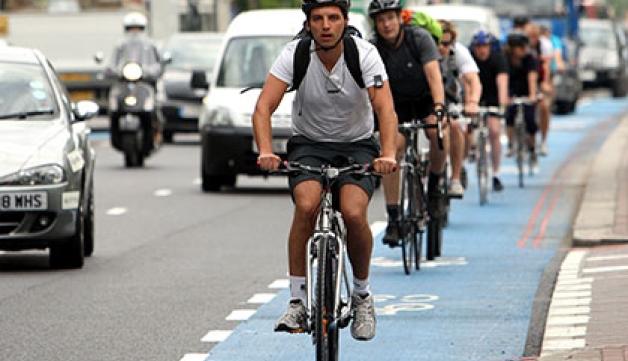 Cyclists ride on a cycle superhighway in London, alongside cars